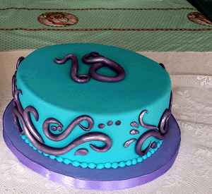 Blauwe verjaardagstaart met paarse decoratie