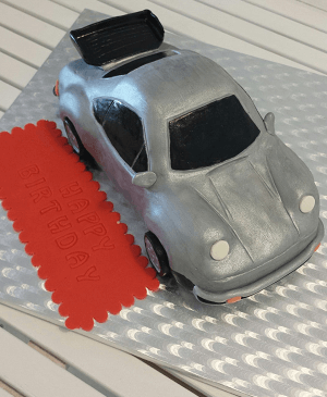 Een zilvere verjaardagstaart in de vorm van een auto