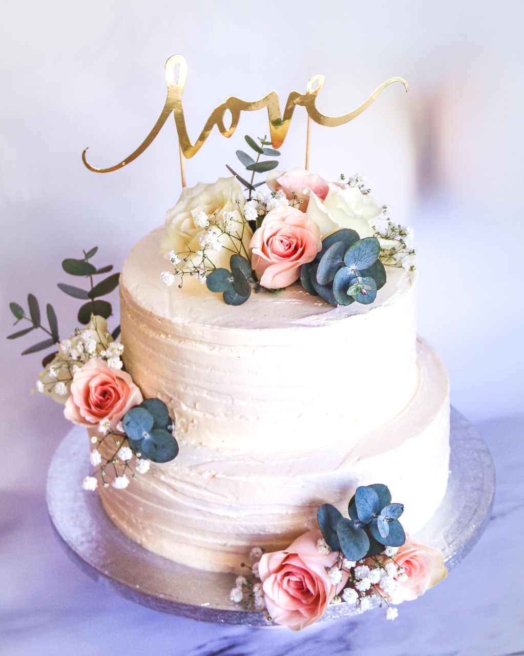 witte-structuur-streepjes-botercrème-taart-met-zacht-roze-bloemen-en-goud-love-taart-topper